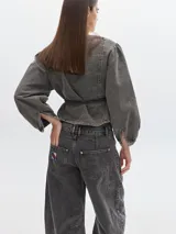 Blusa crop de denim color marrón con efecto lavado, de manga larga abullonada, escote en V y lazo en la cintura.