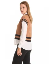 Buzo combinado de estilo preppy que simula un conjunto de sweater tejido con camisa debajo. Presenta un cuerpo de punto color marrón con escote en V y ribetes negros en cuello, sisas y ruedo, integrado con cuello, mangas largas y bajo de gasa blanca.