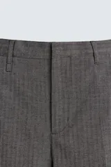 Pantalón de vestir con corte flare y ajuste relajado, confeccionado en tejido con viscosa y patrón de espiga. Cuenta con bolsillos frontales, bolsillos traseros de vivo y cierre frontal con cremallera y botón.