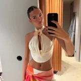 Top halter de color crema con diseño drapeado en el frente y detalle de flor aplicada en el cuello.