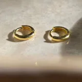 Par de aros pequeños dorados, tipo argolla, con cierre a presión.