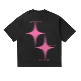 Remera oversize negra con estampado trasero en color rosa vibrante. El estampado incluye dos figuras de estrella con efecto de brillo y texto en cursiva que dice "Limits are optional", "Rush the moment" y "Own the night".
