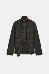 Chaqueta de estilo safari confeccionada en mezcla de algodón con acabado encerado. Presenta cuello alto con trabilla ajustable y hebilla metálica, cierre frontal con cremallera y botones ocultos bajo solapa, bolsillos de plastrón con solapa en el delantero y cinturón ajustable del mismo tejido para anudar en la cintura.