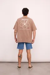 Remera verde militar de corte oversize con cuello redondo y estampado en la espalda con el logo de Brixton, una flor de hibisco y la frase "Where hibiscus grows, peace flows".