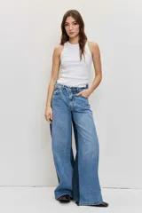 Jean wide leg de tiro medio, confeccionado en denim azul con detalles de paneles laterales en un tono más oscuro, tiro medio, cierre frontal con botón y cremallera, y diseño de perneras amplias.