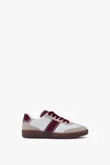 Zapatilla urbana de mujer con base de goma marrón, capellada en beige y blanco, y detalles bordados en color bordó. Cierre con cordones bordó.