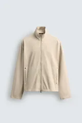 Sudadera de algodón color beige claro con efecto lavado, corte relajado, cuello alto y cierre frontal de cremallera. Presenta bolsillos de vivo en la cadera y mangas largas.