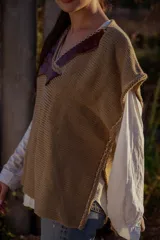 Chaleco tejido color tostado con apliques de cuero marrón en el cuello y detalle de pespunte en el contorno.