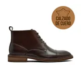 Bota de vestir tipo chukka para hombre, confeccionada en cuero vacuno de color marrón oscuro. Presenta un diseño con cordones, puntera reforzada con costura y suela de madera con acabado rústico.