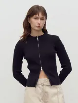 Cardigan de punto acanalado color negro, con cuello redondo y cierre frontal doble que permite abrirlo desde arriba o desde abajo.