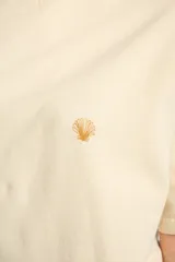 Remera color arena de algodón peinado, corte oversize y manga corta. Estampado pequeño de una concha en el pecho.