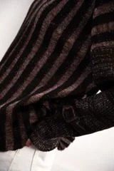 Buzo color beige con rayas horizontales en lurex dorado, cuello con medio cierre, corte oversized y logo tejido en el puño.