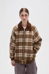 Campera de estilo bomber con cierre frontal, confeccionada en tejido a cuadros en tonos marrones y beige. Presenta cuello camisero en pana marrón, puños y ruedo elásticos acanalados, y bolsillos laterales.