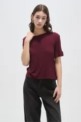Remera de manga corta color bordó, de tejido acanalado, corte al cuerpo, con cuello redondo y delicados volados en los puños.
