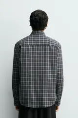 Camisa de corte relajado confeccionada en voile de algodón, con estampado de cuadros. Presenta cuello solapa, manga larga con puños abotonados, bolsillo de parche en el pecho y cierre frontal de botones.