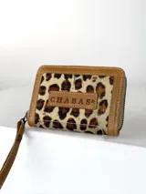 Mini billetera de cuero con textura efecto cocodrilo y cierre perimetral. Presenta un parche central con el logo de la marca grabado.