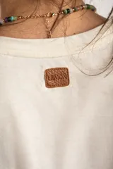 Remera de algodón peinado color marfil, de manga corta y corte al cuerpo, con escote en V ribeteado con hilo dorado.