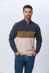 Remera polo de manga larga con diseño de bloques de color en azul marino, marrón y beige. Presenta cuello alto con cierre frontal parcial y estampa frontal con el logo de la marca.