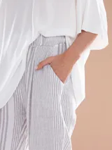 Pantalón de lino a rayas verticales color gris y blanco, con cinturón de la misma tela.
