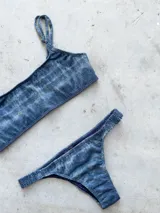 Conjunto de bikini con estampado geométrico en blanco y negro, compuesto por un top bandeau alto con breteles regulables y lazo en la espalda, y una bombacha vedetina con frunce elástico en los costados.