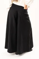 Pantalón de corte palazzo en color negro, con cintura alta, cierre frontal con botón y costuras verticales que definen su estructura amplia.