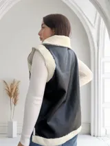 Chaleco negro de ecocuero con interior de corderito blanco, cierre frontal con cremallera y bolsillos laterales.