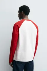Camiseta de corte relajado con diseño color block, cuello redondo y mangas largas tipo raglán en contraste.