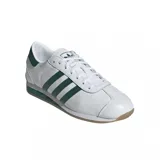 Championes adidas Country II de diseño clásico, color blanco con las icónicas tres tiras laterales y detalles en el talón en color verde. Presentan suela de goma color caramelo y entresuela blanca con una franja verde.