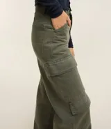 Pantalón wide leg de sarga color marrón chocolate, tiro alto, con bolsillos laterales tipo cargo y etiqueta con lettering en la cintura.