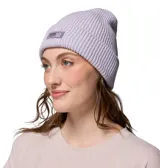 Gorro tipo beanie de tejido acanalado en color lila, con parche rectangular de la marca Columbia en el frente.