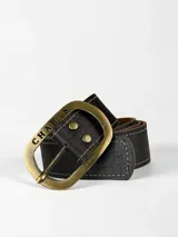 Cinto de cuero 100% genuino en color marrón oscuro con textura efecto cocodrilo, costuras decorativas en los bordes y hebilla grande de metal envejecido con la inscripción de la marca.