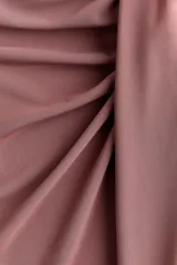 Pollera midi de punto suave, color rosado, con cintura elástica de tiro alto y detalle drapeado frontal con abertura asimétrica.