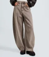 Pantalón de jean con corte barrel, de cintura alta y diseño de piernas anchas con volumen redondeado. Presenta bolsillos funcionales, trabillas para cinturón y cierre frontal con botón y cremallera.