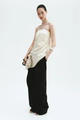 Top strapless de satén color beige, con diseño ceñido, drapeado lateral en la cintura y bajo asimétrico.