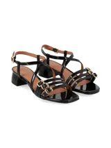 Sandalias Celeste de taco bajo y ancho, confeccionadas en cuero charol negro. Presentan múltiples tiras delgadas cruzadas sobre el empeine y tres hebillas metálicas decorativas en la parte frontal.
