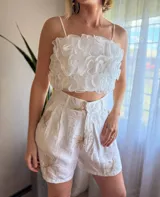 Shorts de tiro alto color marrón con estampado de pequeños rombos blancos y un borde ancho con diseño de encaje o bordado estilo paisley en blanco.