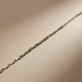 Pulsera de cadena fina con eslabones de plata intercalados con pequeños detalles en oro, diseño minimalista y elegante.