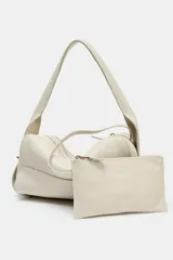 Bolso alargado de piel color blanco hueso, con asa de hombro y cierre de cremallera.