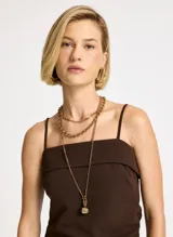 Blusa marrón de punto elástico con corte ajustado, escote recto, tirantes finos, detalle de panel superpuesto en el busto, costura lateral con ligero drapeado, bajo asimétrico con punta lateral larga y pespuntes.