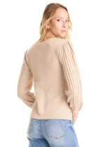 Buzo de tejido lurex en color beige, con cuello redondo y mangas largas con diseño plisado y puños con aplique de botones dorados.
