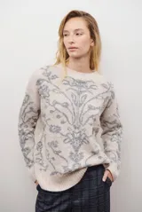 Buzo de tejido de punto en color marrón con un patrón ornamental floral en color celeste. Presenta cuello redondo, mangas largas y un corte holgado.