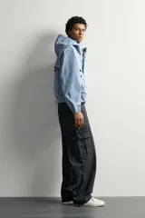 Cazadora cropped fit de tejido técnico negro repelente al agua, con cuello subido, capucha ajustable, bolsillos frontales de plastrón con solapa, mangas largas con puños elásticos y bajo ajustable con cordón.