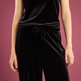 Pantalón de corte ancho y fluido confeccionado en terciopelo negro, con cintura de tiro medio y cierre frontal.