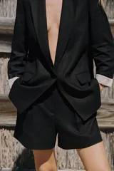 Shorts color beige confeccionados en hilatura con lino, de tiro alto. Presentan bolsillos delanteros, falsos bolsillos traseros con solapa y pinzas delanteras. Cierre frontal con cremallera y gancho metálico.