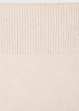 Falda midi de tejido de punto en color beige, con diseño recto de tiro medio y cierre de cremallera frontal que crea una abertura en el bajo.