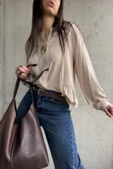 Camisa beige de manga larga con detalles de vainica vertical en el frente y cierre frontal de botones.