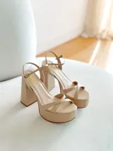 Sandalias de cuero sintético color manteca, con plataforma y tacón bloque. Presentan tiras cruzadas en el empeine y pulsera con hebilla al tobillo.