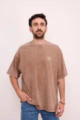 Remera verde militar de corte oversize con cuello redondo y estampado en la espalda con el logo de Brixton, una flor de hibisco y la frase "Where hibiscus grows, peace flows".