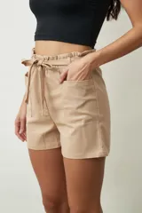 Short de tiro alto con estampado botánico en tonos verdes y crudos. Presenta una cintura elástica con lazo ajustable del mismo tejido, bolsillos laterales y un corte holgado.