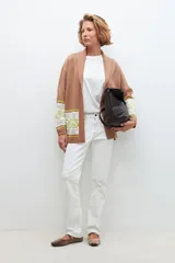 Ruana color tostado con guarda jacquard floral en mangas y bolsillos.